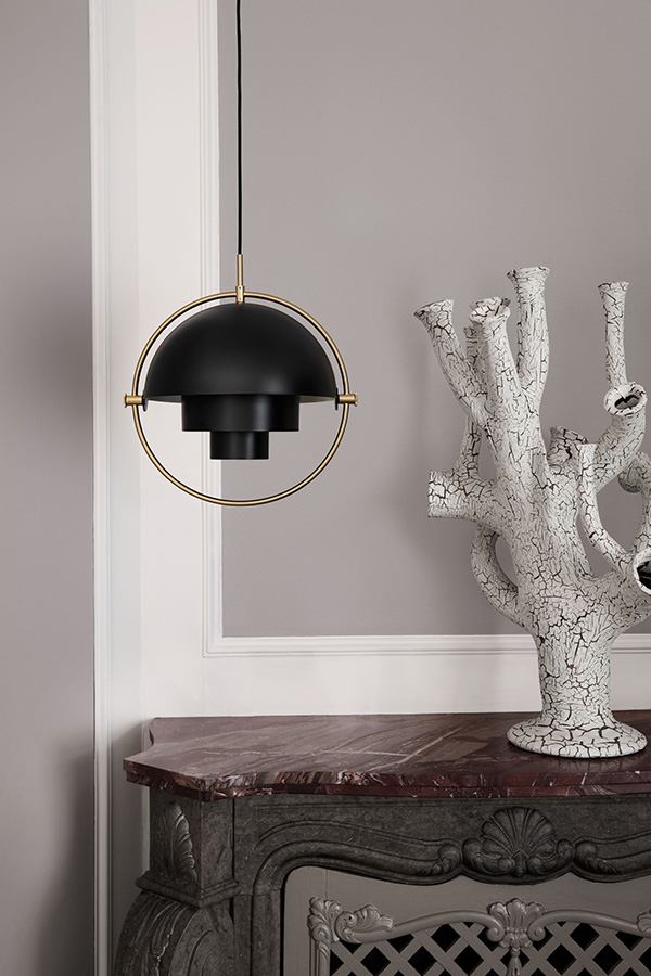 Gubi multi lite in brass and black above a fireplace