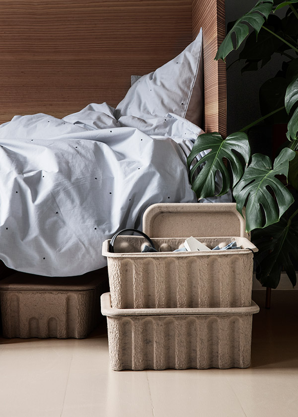 Ferm Living's stackable paper pulp boxes next to a wooden bed