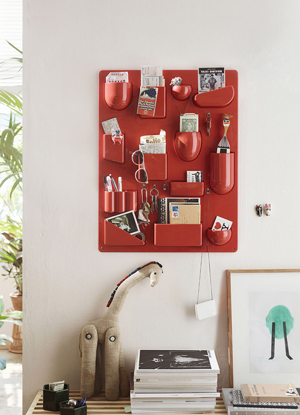 Red Vitra UtenSilo wall storage unit above a toy giraffe and a pile of books