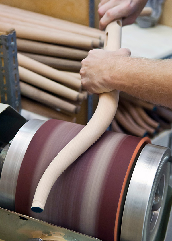 Someone sanding a wooden component of a CH24 wishbone chair