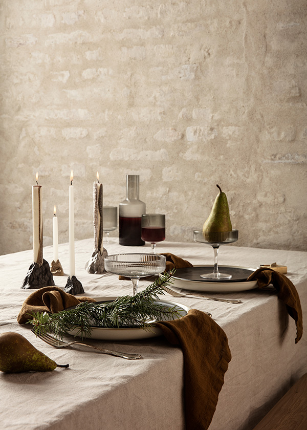 A Ferm Living festive dining table with candles and pears in cocktail glasses