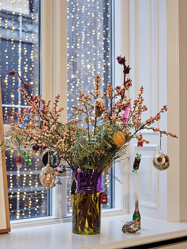 A HAY Moroccan Vase filled with festive foliage on a windowsill