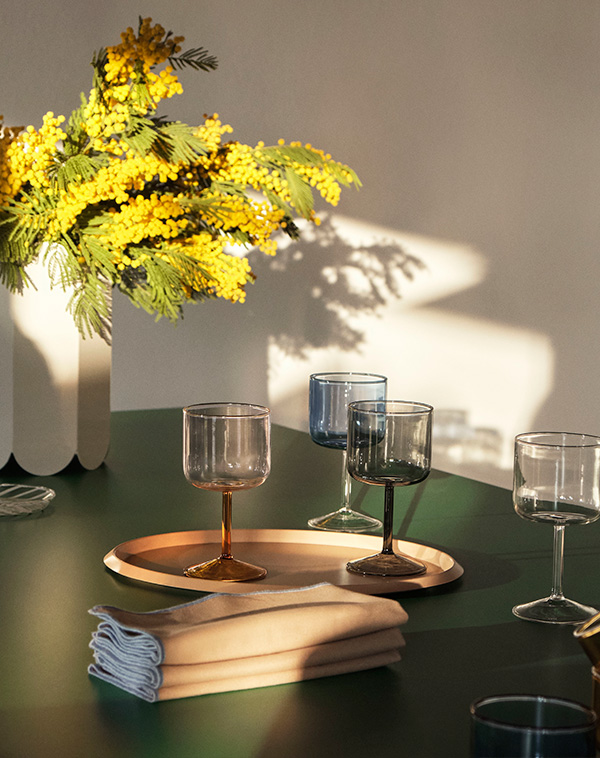 A selection of HAY Tint wine glasses on a green dining table