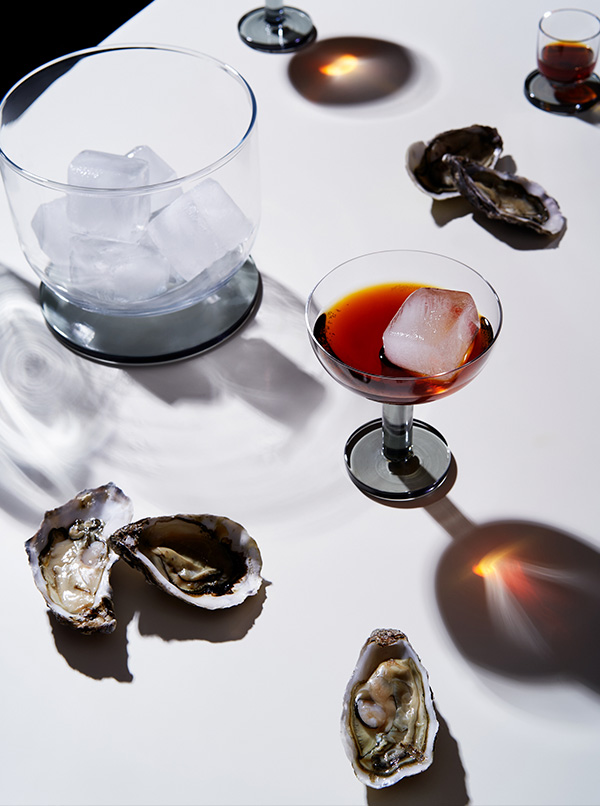 A Tom Dixon Puck glass surrounded by oysters on a dining table