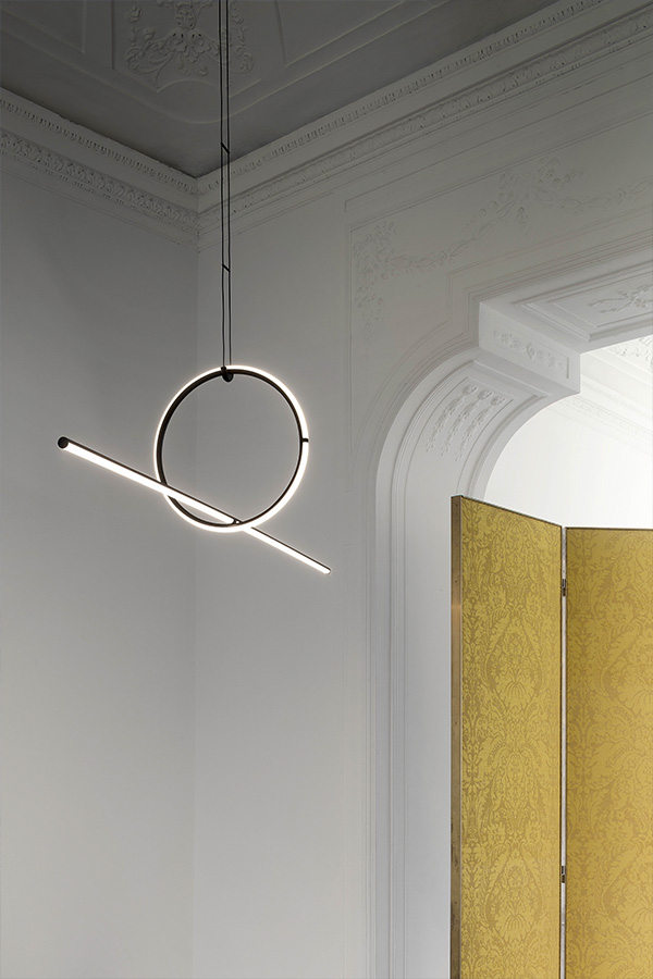 A Flos arrangements light in a white room next to a gold room divider