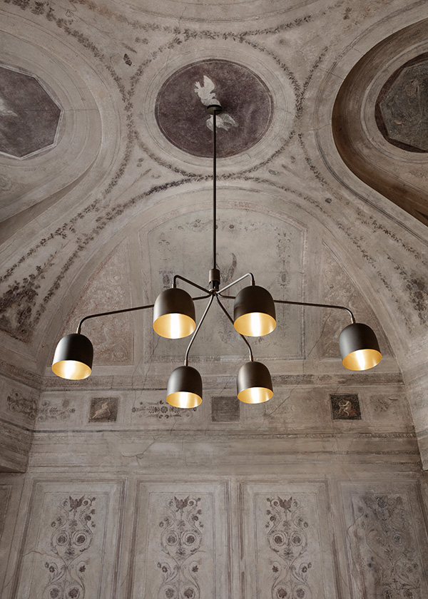 GUBI Howard chandelier hung from an ornate ceiling