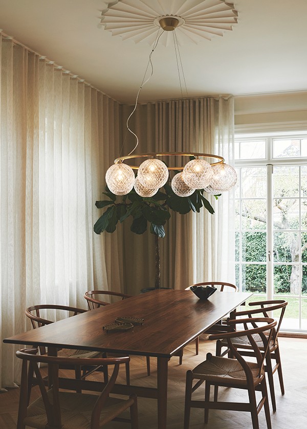 Nuura Miira 8 Chandelier above a walnut dining table set
