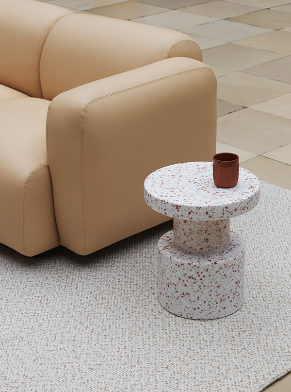 A Normann Copenhagen bit stool next to a sofa