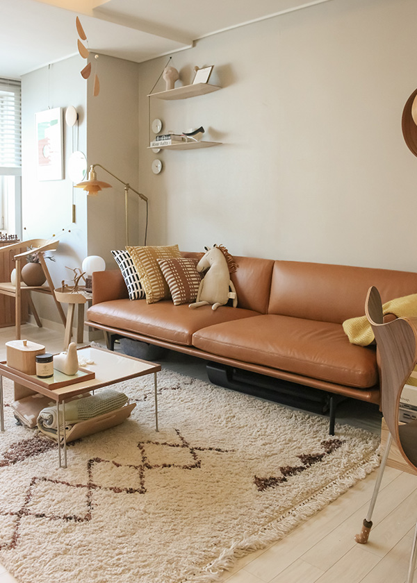 A brown leather sofa inside a neutral Korean apartment