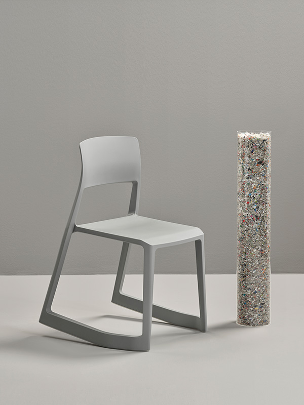 A grey Vitra Tip Ton RE chair next to a tube of recycled plastic