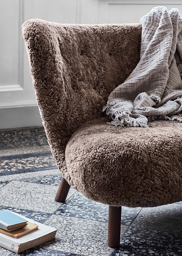 A close up of the &Tradition VB1 Little Petra Lounge Chair on a tiled floor