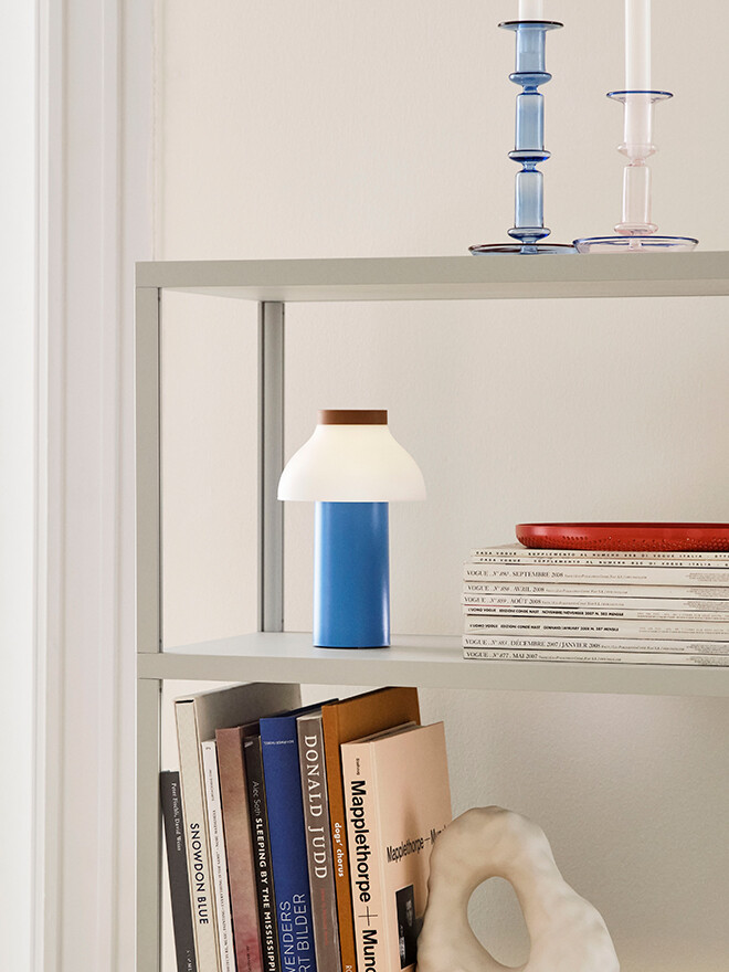 Shelving unit with books and HAY PC Portable Table Lamp