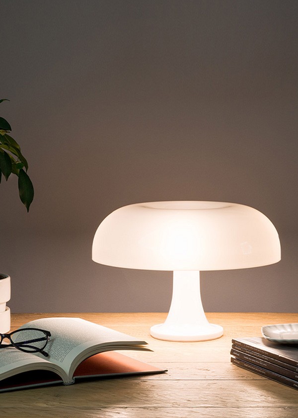 Artemide Nessino Lamp switched on in white on desk