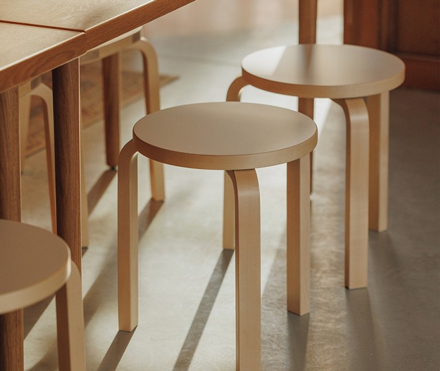 Artek 60 stool lined up against dining table in sunlit setting