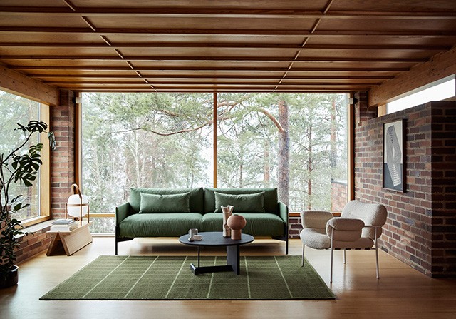 Green 3-seater sofa, white lounge chair and black coffee table in an exposed brick living room.