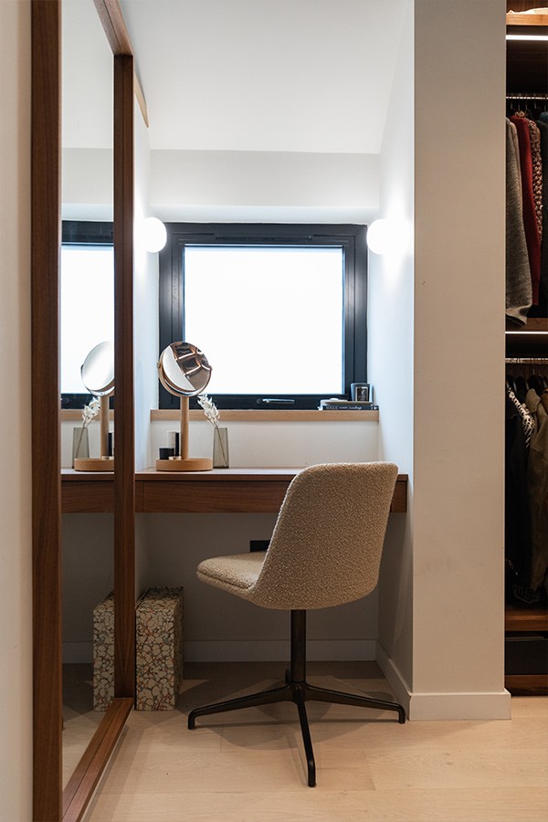 Wooden vanity nook with a small makeup mirror, a beige upholstered swivel chair, and a full-length wooden mirror.