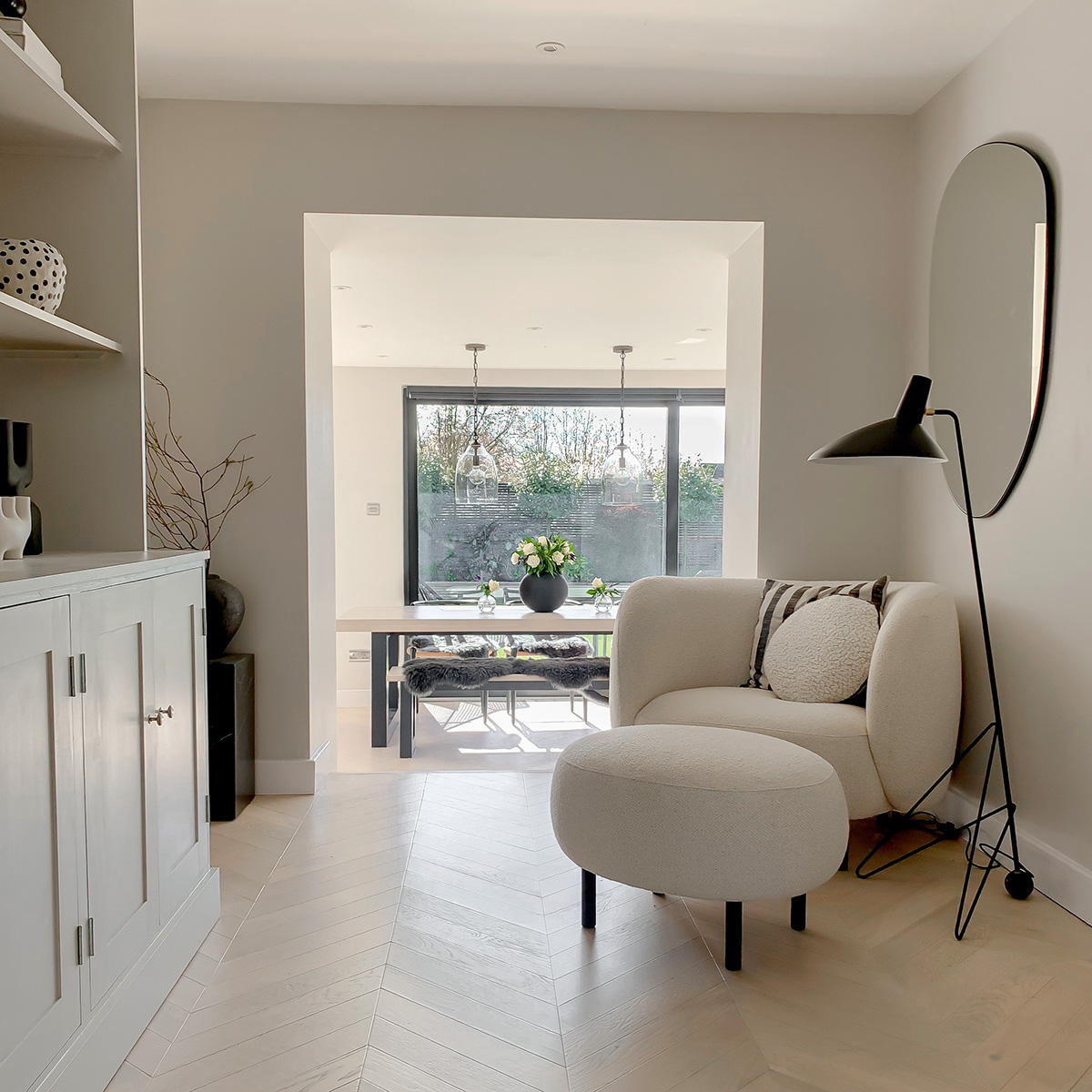 A curvy white lounge chair next to the &Tradition HM8 Tripod Floor Lamp