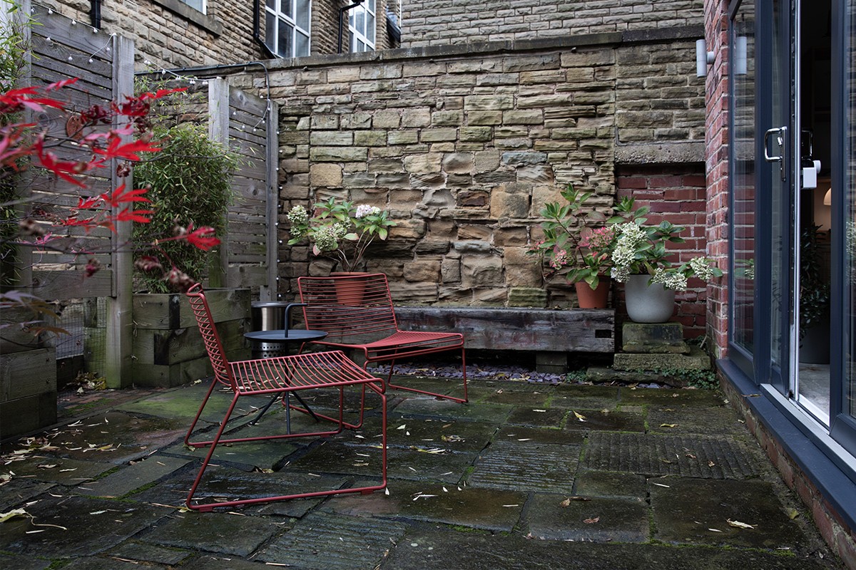 2 rust red HAY Hee Lounge Chairs in a small outdoor area with stone paving