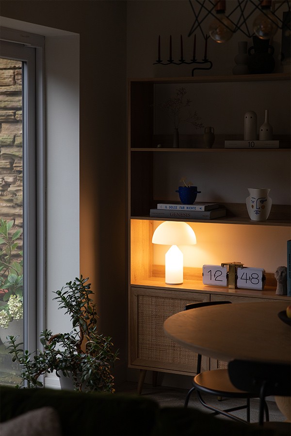 Glass Oluce Atollo Table Lamp illuminating a wooden shelving unit