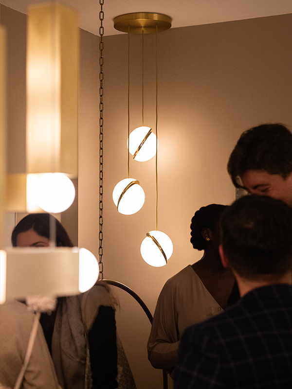 The Lee Broom Mini Crescent Chandelier surrounded by people