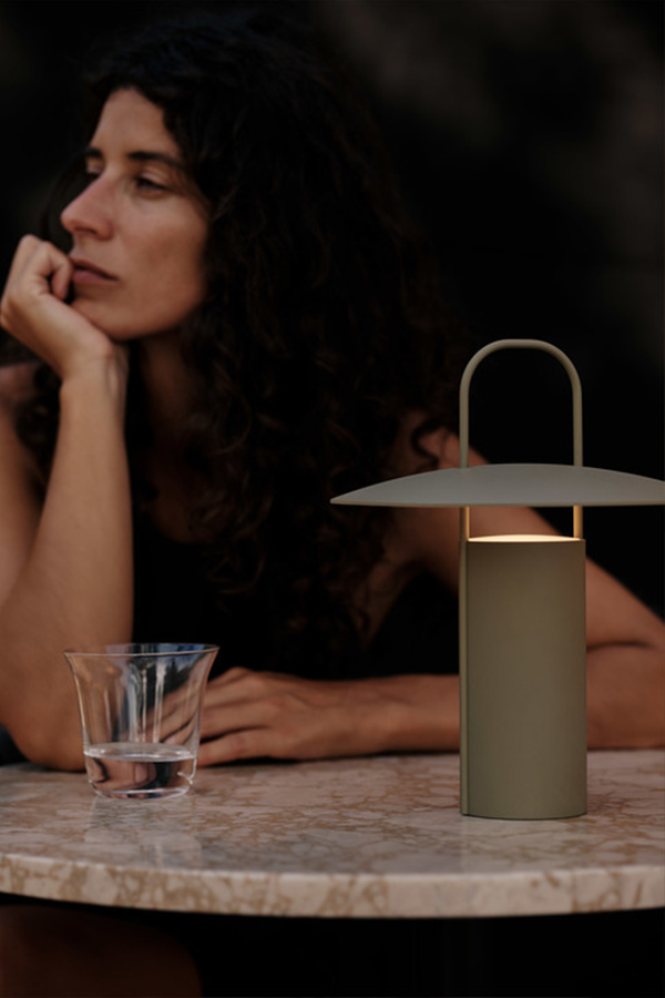 Woman sat at a table with Audo Copenhagen Ray Table Lamp