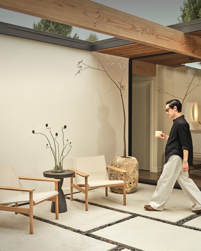 Man approaching set of two Skagerak by Fritz Hansen lounge chairs in serene setting 