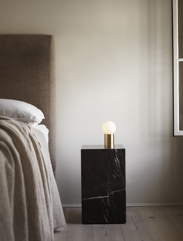 Menu Socket Occasional Table Lamp on marble plinth in a bedroom