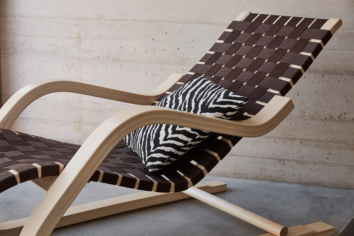 A close up shot of an Artek 43 Lounge Chair, with a wooden frame and webbed seat