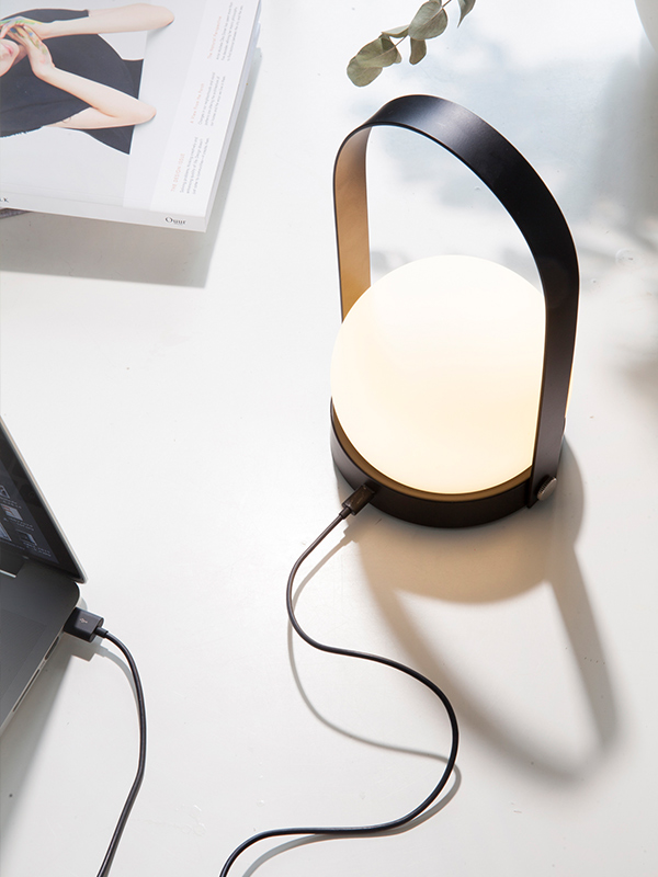 Audo Copenhagen Carrie LED Table Lamp being charged by a laptop