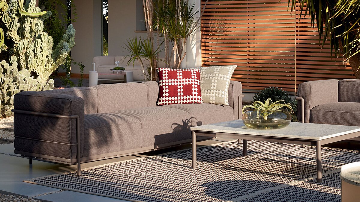 An outdoor living room with grey sofa and Cassina LC10-P Coffee Table