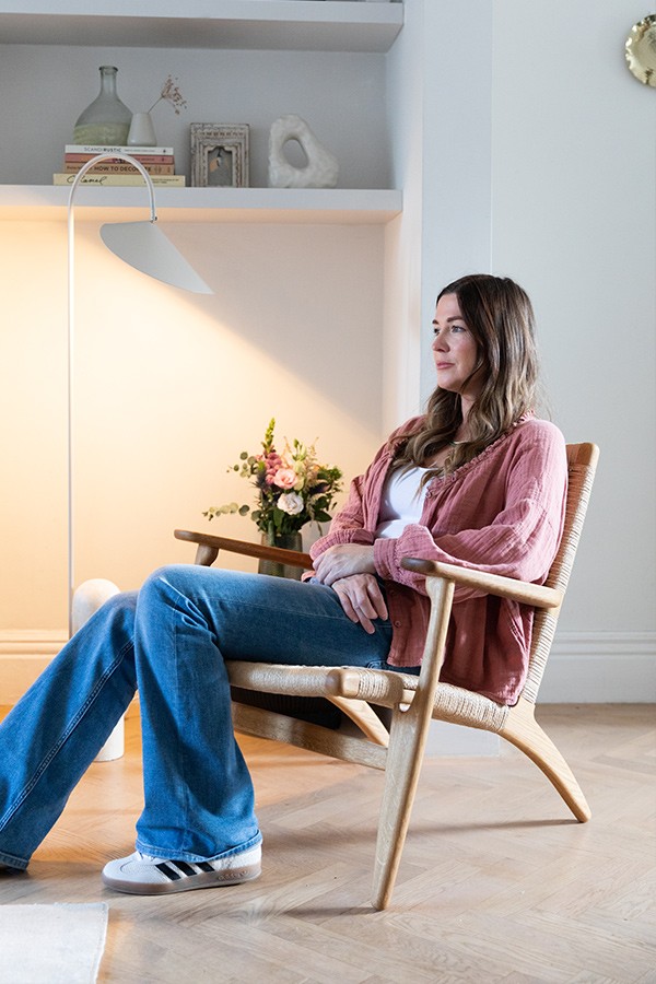 Woman sitting in a Carl Hansen CH25 Lounge Chair beside a floor lamp