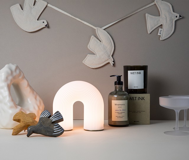 Audo Copenhagen Jwda Portable with ferm LIVING Moire Vase, New Works Aura Table Mirror and Paper Collective Composition Collection 02 Print grouped against a pale green backdrop. 