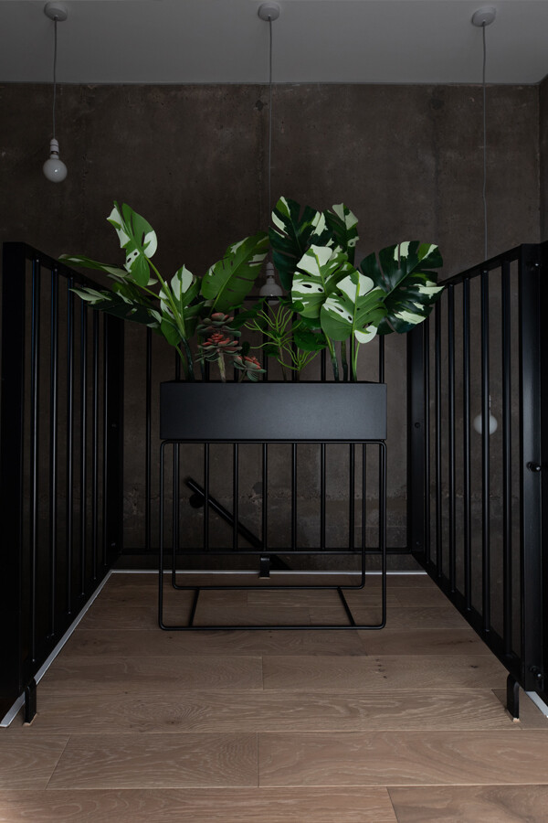 A black Ferm Living plant box surrounded by black railings