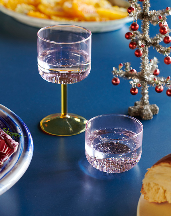 A HAY Tint wine glass and glasses on a blue dining table