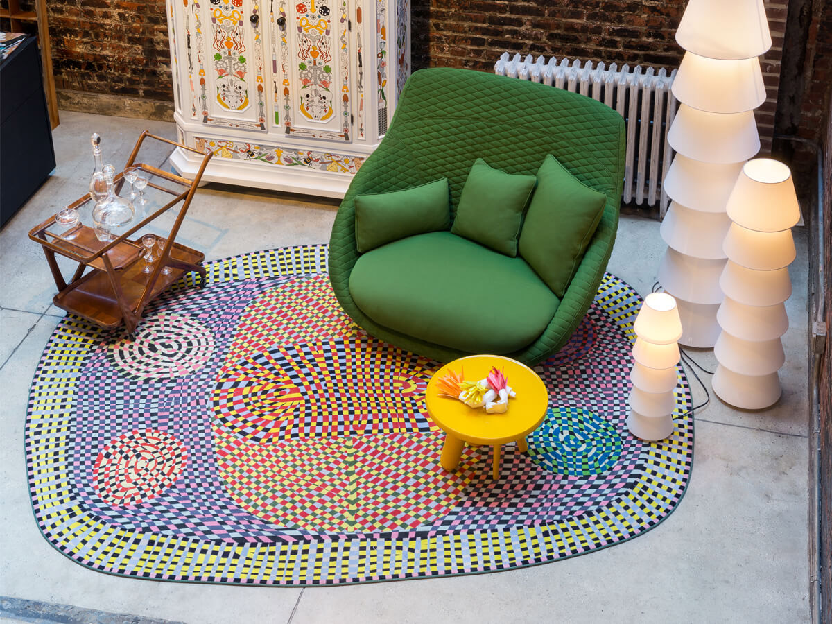 The Moooi Carpets Magic Market Wild Rug under a bright green lounge chair