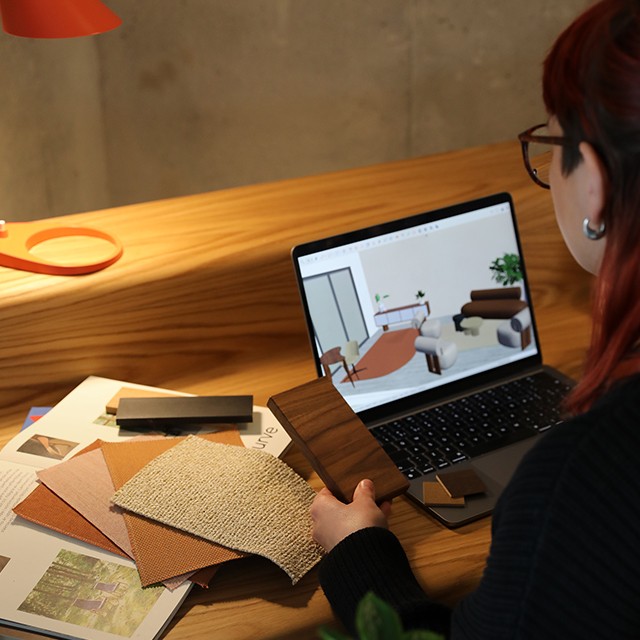 Interior stylist Ashlee creating a CAD roomset for a client, at her desk surrounded by samples. 