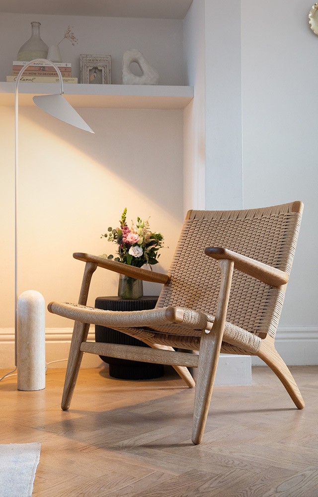 Carl Hansen CH25 Lounge Chair in cosy living setting with wood fire and floor plant 