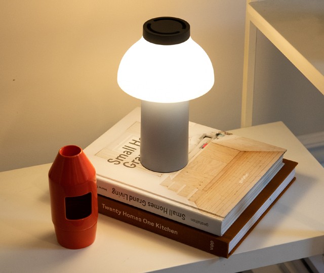 HAY PC Portable Light pictured on top of design books on a bookshelf 