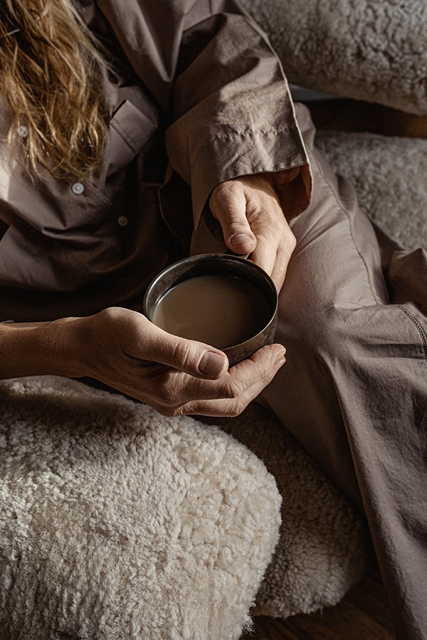 Close up of lady sitting in Brasilia Lounge Chair in sheepskin finish with a cup of coffee