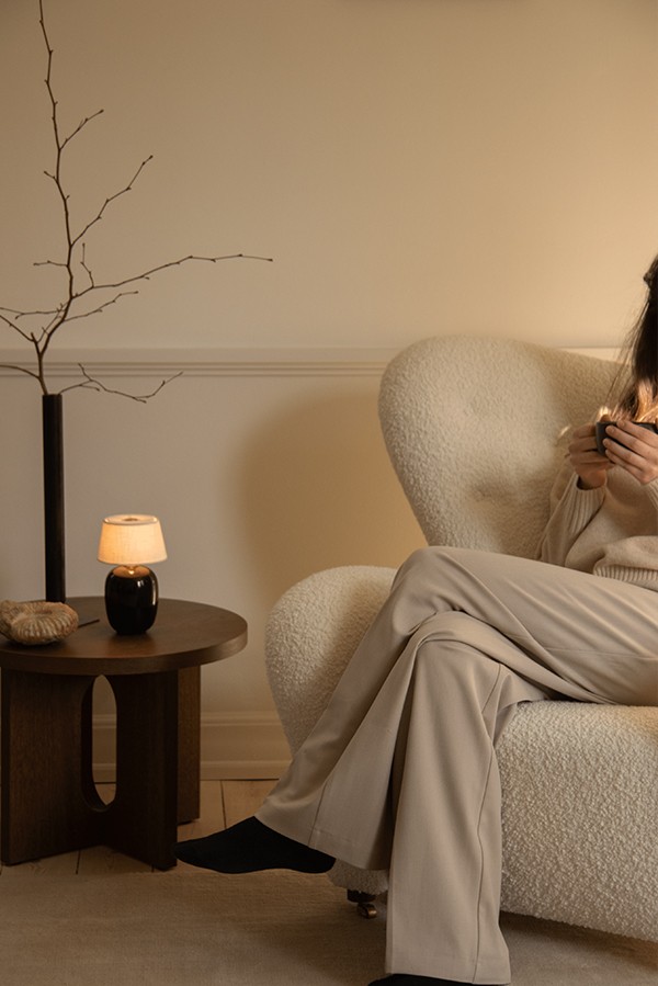 Lady sitting relaxing in the Tired Man Lounge Chair in Boucle upholstery