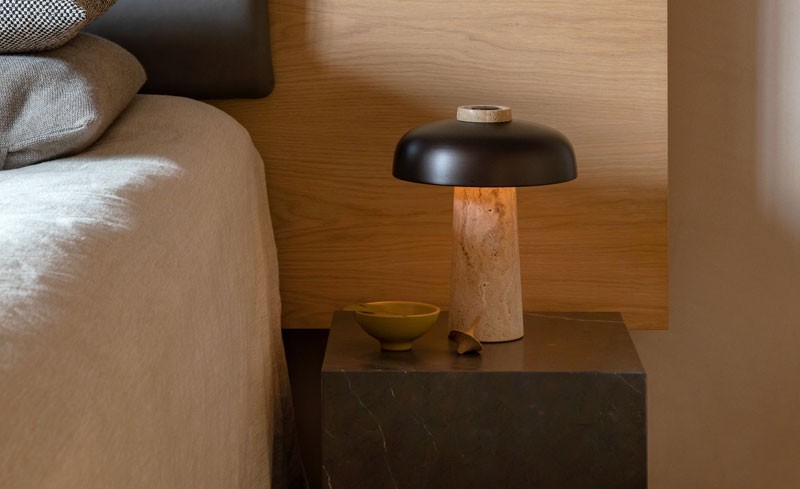 Stone and metal table lamp on a table next to a bed
