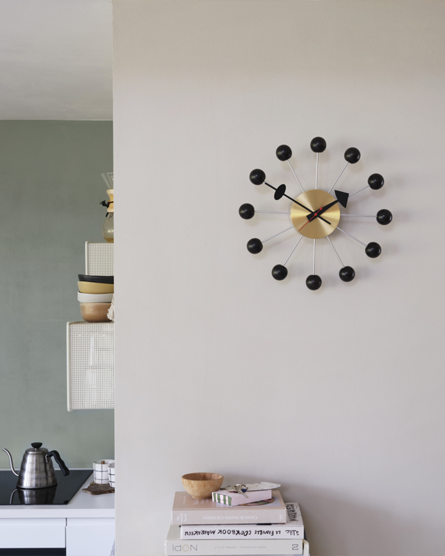 Vitra Eames Ball Wall Clock in green and cream painted kitchen with shelving and books