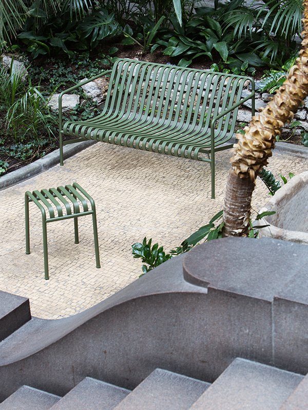Hay Palissade Outdoor Bench in olive green in a courtyard