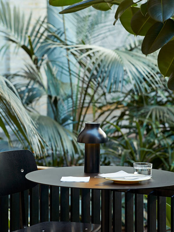 The portable HAY PC Table Lamp on a dining table outdoors