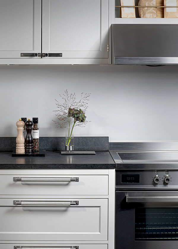 White kitchen space with Buster + Punch pull bar handle with plates and kitchen accessories